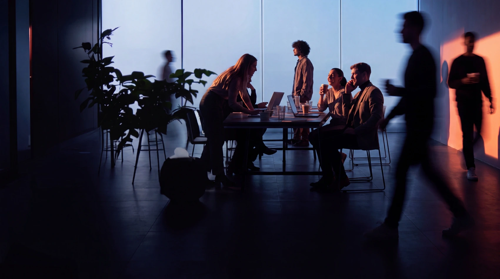 Colleagues in motion around a table with laptops in a dimly lit office, illustrating the MVP Development service
