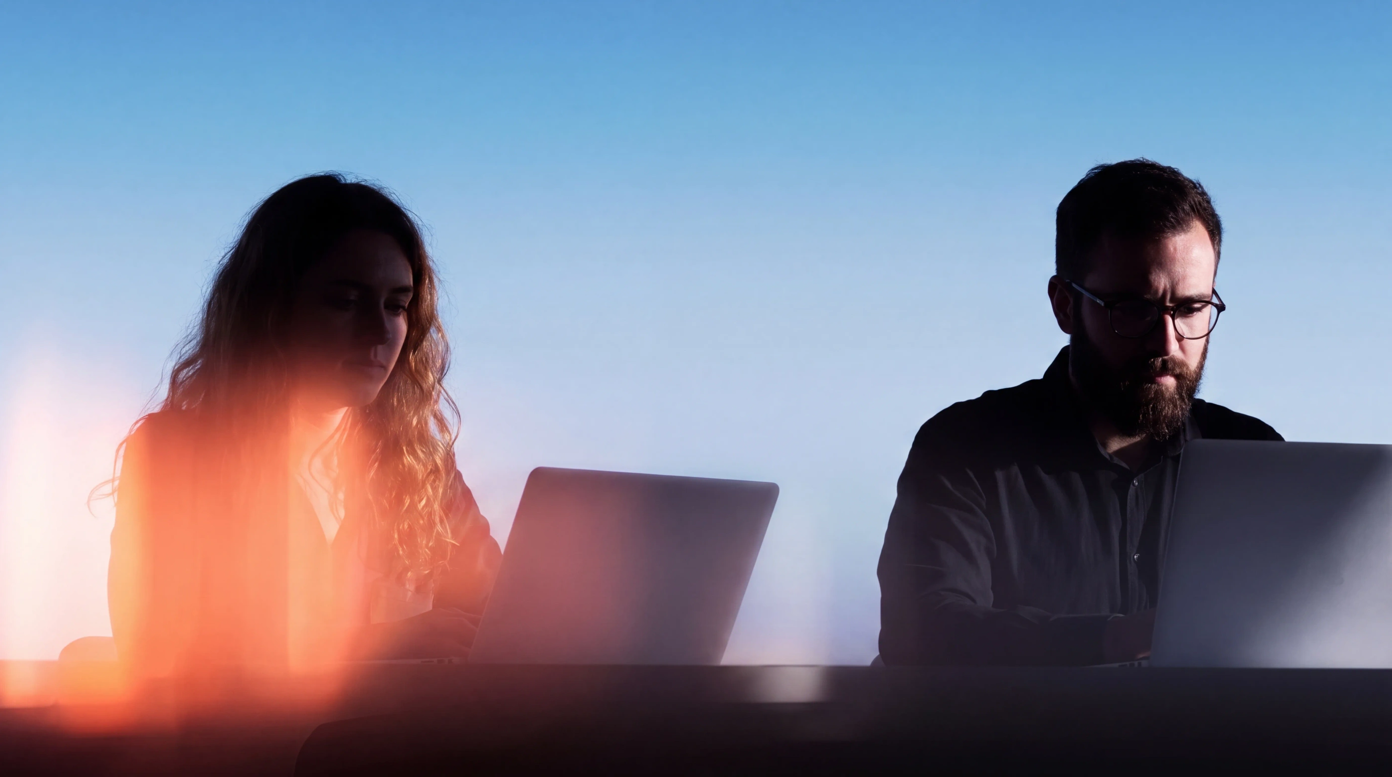 Two software engineers focused on their laptops in a modern workspace