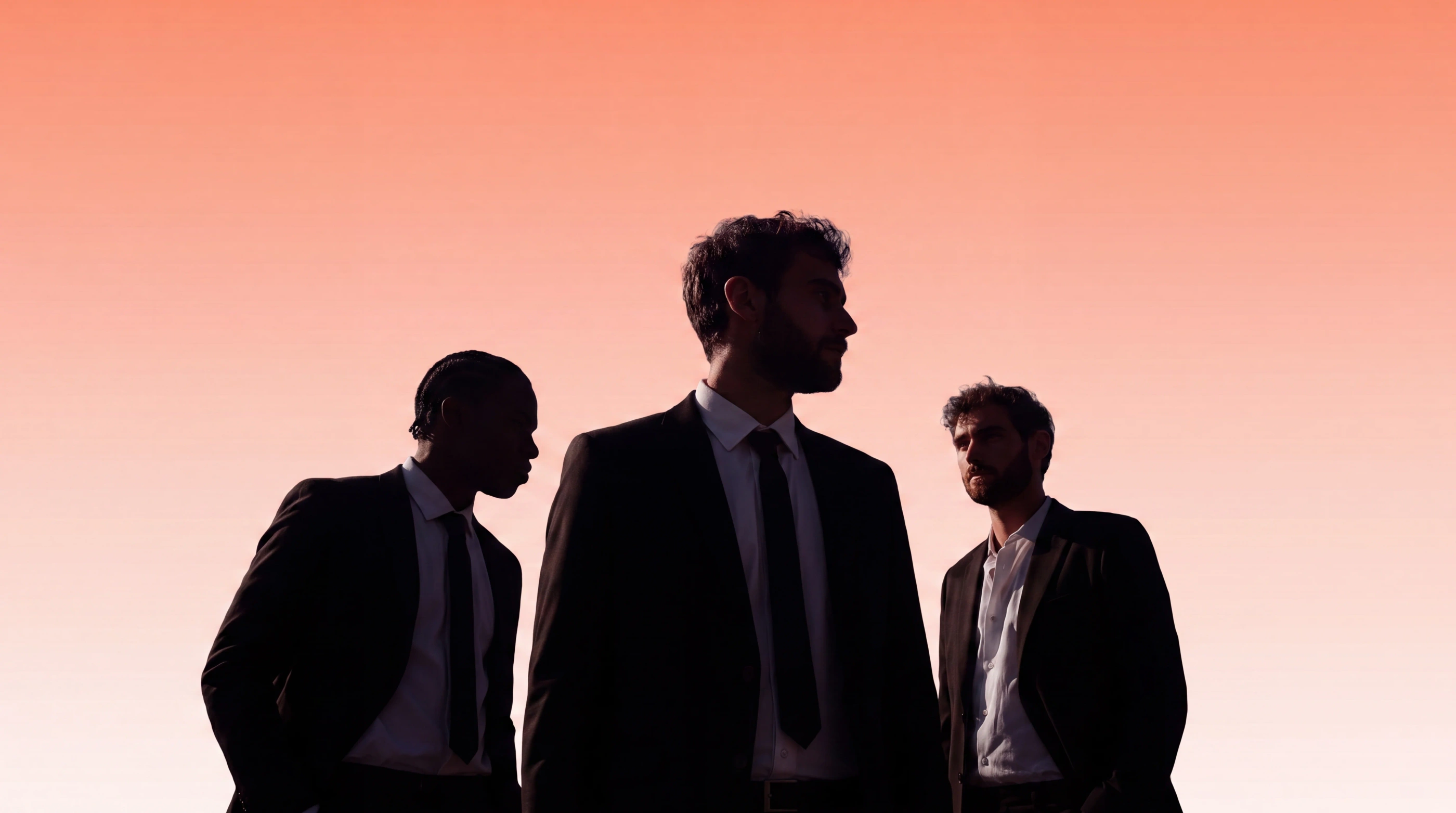 Three suited legal professionals in discussion against a warm sky