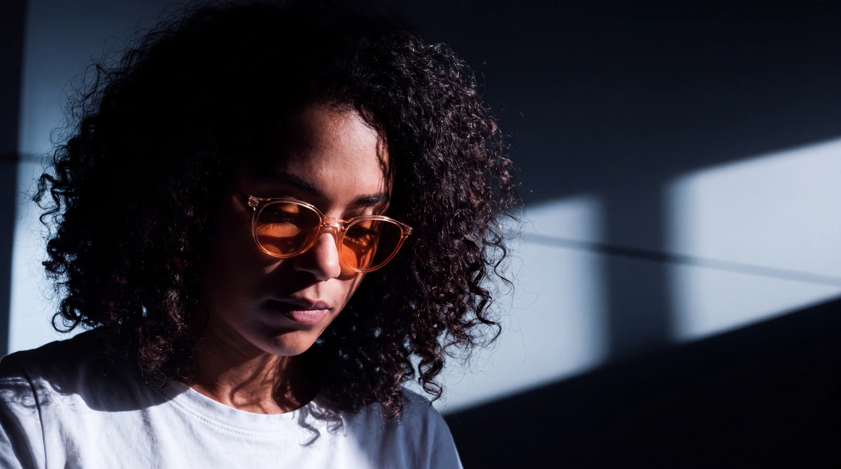 Close-up portrait lit by dramatic side light through amber-tinted glasses, illustrating the Maintenance & Support service